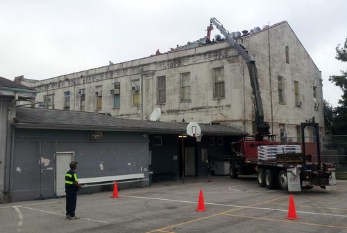 Workers patch the roof of the old Carrollton courthouse building Saturday morning so Audubon Charter School can use it for a few more months. (Robert Morris, UptownMessenger.com)