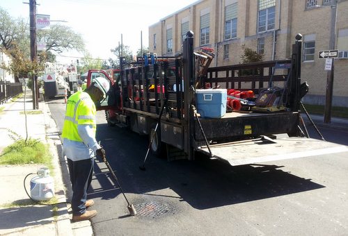 A construction worker touches up the area around a drain cover on a newly repaved section of Freret Street on Friday afternoon. (Robert Morris, UptownMessenger.com)