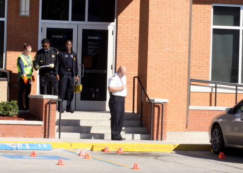 Investigators place evidence cones in the parking lot of the Chase bank at Carrollton and Claiborne after an armored-car guard was fatally shot Wednesday morning. (Robert Morris, UptownMessenger.com)
