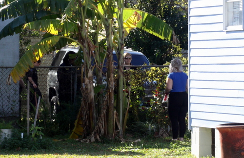 Police speak to neighbors after a large SUV was found ditched in an Adams Street backyard. (Robert Morris, UptownMessenger.com)