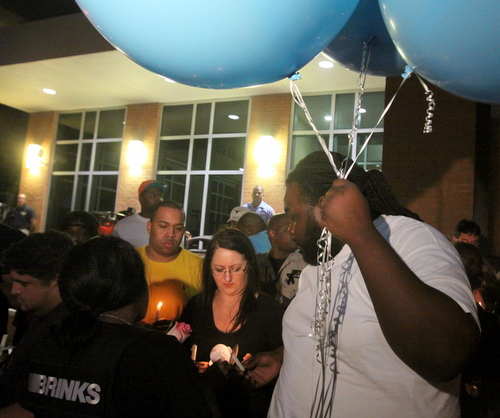 Justin Rivers carries large blue balloons that read, "RIP Hector." (Robert Morris, UptownMessenger.com)