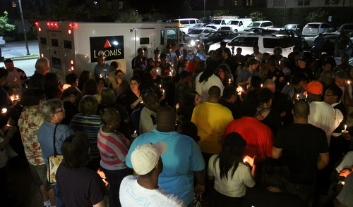 Mourners gather between two Loomis trucks at the vigil. (Robert Morris, UptownMessenger.com)