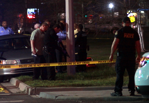 Police examine a shotgun recovered from the scene of a fatal shooting on South Claiborne Avenue. (Robert Morris, UptownMessenger.com)