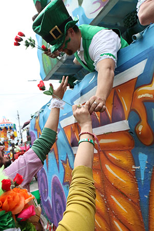 Parade goers receive roses from "Eddies Irish Cajuns"