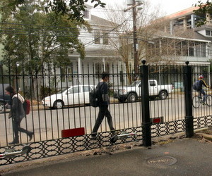 Pedestrians pass by the Newcomb Boulevard fence in early February. (UptownMessenger.com file photo)