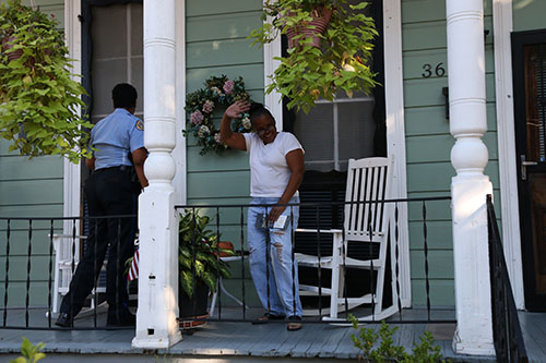 Officer Erica Whitley delivers a crime stoppers pamphlet to Ella Adams Gaynor on the porch of her mother's home on Laurel street. (Zach Brien, UptownMessenger.com)