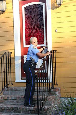 Officer Anya Hilliard leaves a crime stopper pamphlet at a home on Constance street. Hilliard has been serving the sixth district for five and a half years. Because she grew up there, Hilliard says she takes her job personally. (Zach Brien, UptownMessenger.com)