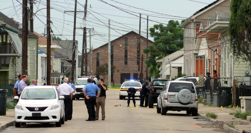 Crime-scene technicians photograph evidence marked by yellow cones in the road and on the sidewalk after a shooting Wednesday afternoon at the intersection of St. Andrews and South Liberty streets in Central City. (Robert Morris, UptownMessenger.com)