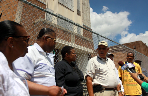 Retired Lt. Gen. Russell Honore (center) and other advocates discuss contamination in the soil at the former Booker T. Washington site in front of what remains of the former school. (Robert Morris, UptownMessenger.com)