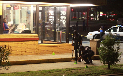 New Orleans police investigate a shooting Sunday night in front of the Church's Chicken restaurant in the 1500 block of South Claiborne. (Robert Morris, UptownMessenger.com)