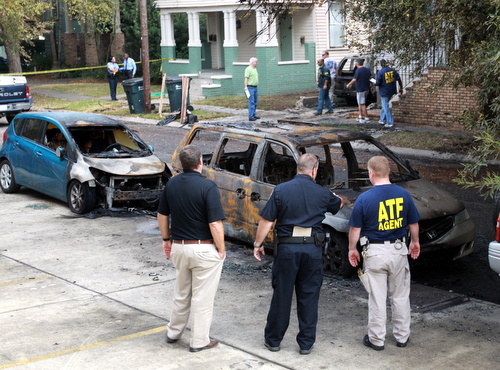 Investigators surround one of the cars that burned across the street from the house. (Robert Morris, UptownMessenger.com)