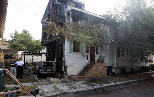 State and local investigators examine the remains of a car parked in a driveway off Constantinople at the corner of Pyrtania Street. (Robert Morris, UptownMessenger.com)