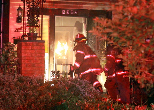 Firefighters enter a house on South Miro to extinguish flames inside. (Robert Morris, UptownMessenger.com)