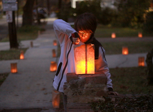 Eli Pirner lights one of several hundred candles on Pine Street on Christmas Eve. (Robert Morris, UptownMessenger.com)
