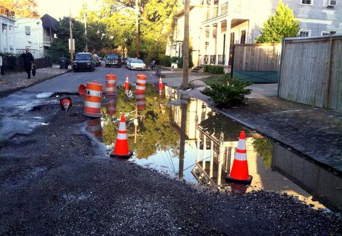 A sinkhole stretches across Coliseum Street while orange cones mark the city's response. (Owen Courreges for UptownMessenger.com)