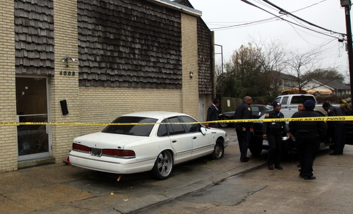 New Orleans police officers look for evidence around a black Honda Accord in the 4000 block of Eden Street, where bullet holes were visible in a glass door of one of the buildings. (Robert Morris, UptownMessenger.com)