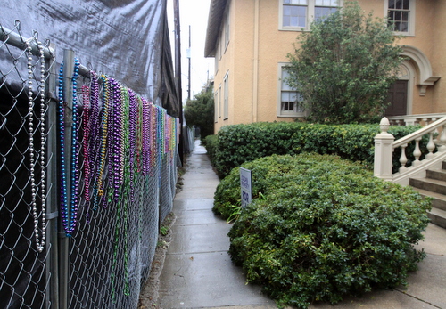 Mardi Gras beads hang on the chain-link fence in front of the tall black tarp, an effort to bring some life back to the otherwise bleak view. (Robert Morris, UptownMessenger.com)