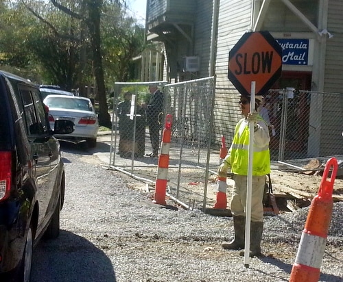 A construction worker guides a passing SUV across Prytania Street on Friday morning. (Robert Morris, UptownMessenger.com)