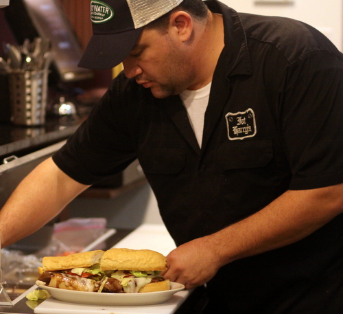 Fat Harry's kitchen manager Jean-Paul Martin prepares a sandwich on Friday afternoon, the first lunch served in the bar since it was destroyed by fire after Hurricane Isaac. (Robert Morris, UptownMessenger.com)