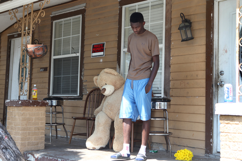 A neighbor drops off a small teddy bear at the home where an 11 year old girl was fatally shot early Monday. (Sabree Hill, UptownMessenger.com)