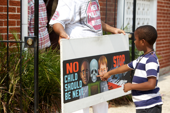 Al Mims, who's father was shot and killed in 1987, stands outside the  funeral and shows a sign reading, "No child should be next. Stop the killing".  (Sabree Hill, UptownMessenger.com)
