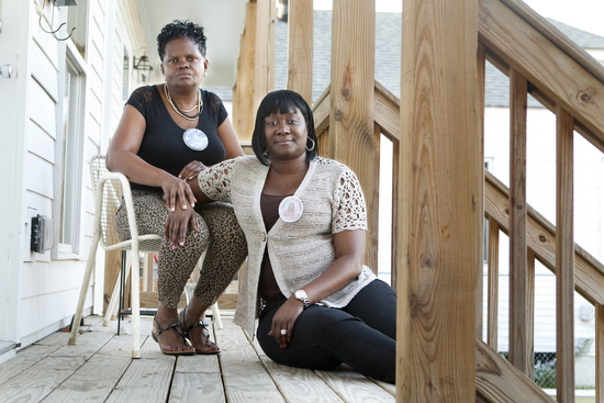 Cathy Rickmon (left) and Martha Bullock (right) sit on the porch where their sons Orlando “Lanny” Rickmon and Desmond O’Neal Bell were murdered on April 23, 2013. "Losing a child is like losing half a heart," said Rickmon. (Sabree Hill, UptownMessenger.com)