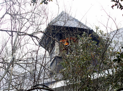 Flames can be seen through an upper-story window.  (Robert Morris, UptownMessenger.com)